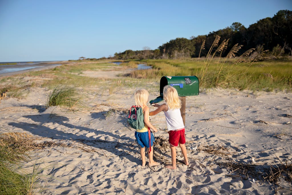 Two children play by a beachside mailbox at Hilton Head Island, enjoying a sunny day outdoors.